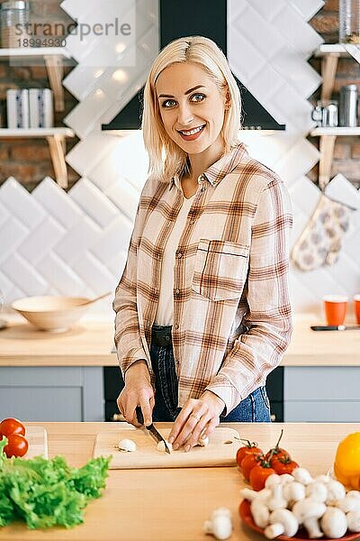 Lächelnde junge Frau kocht gesundes Essen in der Küche zu Hause. Vegane Diät Lebensmittel Konzept