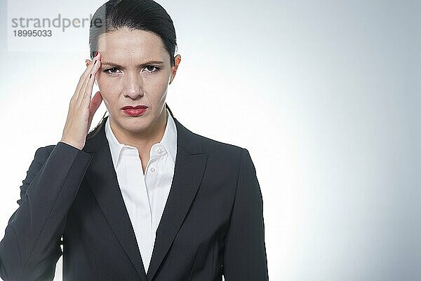 Stilvolle  hübsche Geschäftsfrau mit der Hand an ihrem Kopf  was auf Kopfschmerzen  Stress oder Migräne hinweist