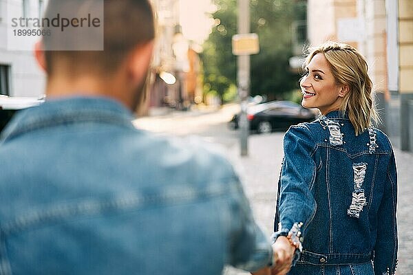 Schöne junge Frau  die auf der Straße geht und einen Mann an der Hand hält. Folgen Sie mir Konzept