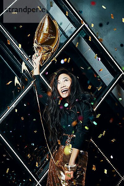 Hübsche glückliche asiatische Frau  die Spaß hat und auf einer Party tanzt und einen goldenen Ballon hält. Feiern Konzept