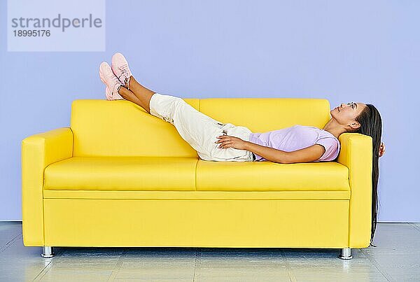 Hübsche asiatische Frau entspannen  nachdem er auf gelben Sofa nach harter Arbeit. Ruhe  Komfort Konzept