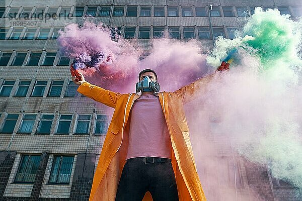 Junger Mann mit Atemschutzmaske hält Rauchbomben in den erhobenen Händen. Protest  Freiheit  Revolution Konzept
