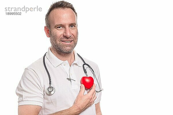 Unrasierter männlicher Kardiologe oder Arzt mittleren Alters  der sich ein rotes Herz an die Brust hält  ein Konzept für eine Untersuchung zur gesunden Lebensweise und Vorsorgeuntersuchung  vor weißem Hintergrund