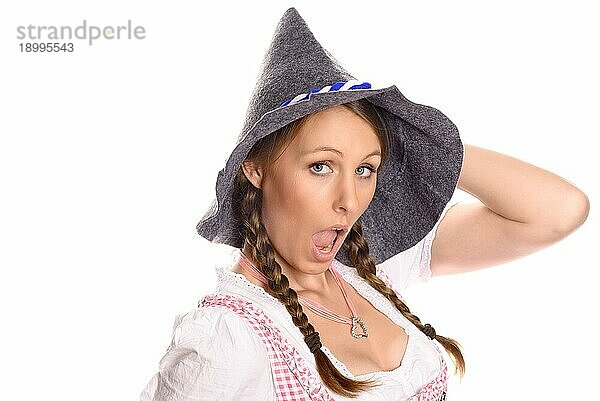 Attraktive Frau in einem traditionellen deutschen oder bayerischen Dirndl und einem rustikalen Partyhut  die eine kecke verführerische Pose einnimmt  während sie mit einem Schmollmund in die Kamera blickt  vor weißem Hintergrund