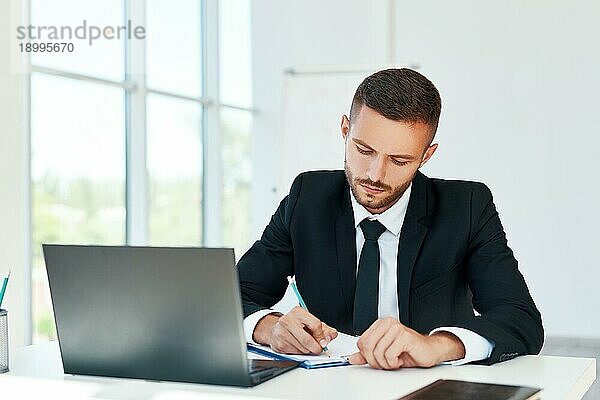 Junger Geschäftsmann bei der Vertragsunterzeichnung und der Arbeit an Dokumenten in einem modernen Büro