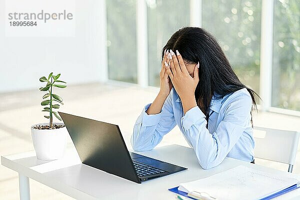 Gestresste müde Geschäftsfrau geschlossen Gesicht von zwei Händen sitzen in modernen Büro. Probleme Konzept
