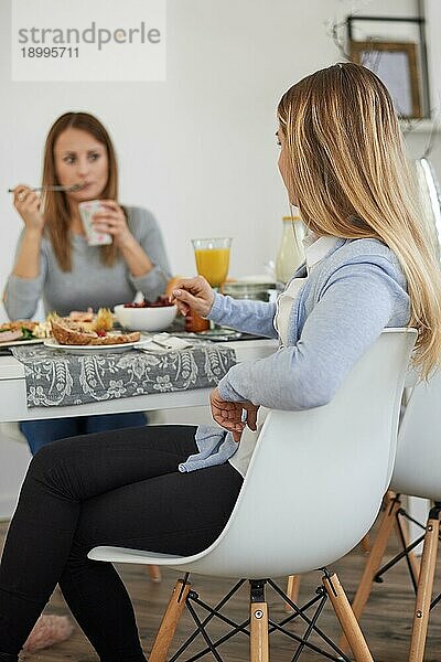 Mutter und Tochter im Teenageralter genießen das Frühstück  während sie Zeit miteinander verbringen und ein Gespräch von Herz zu Herz führen