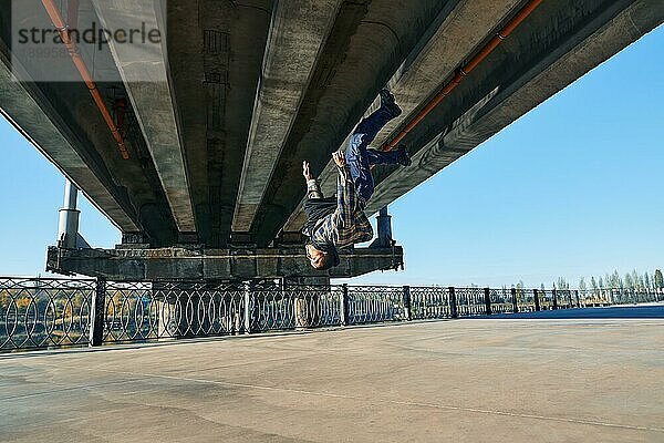 Junger Mann Breakdancer macht Salto akrobatische Stunts tanzen auf städtischen Hintergrund. Straßenkünstler Breakdance im Freien