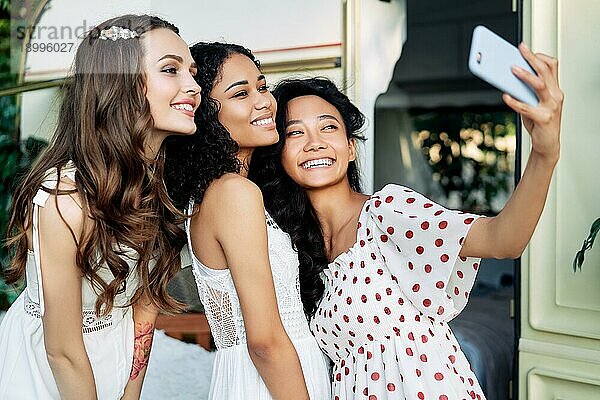Schöne lächelnde Frauen nehmen Selfie mit Handy. Multi ethnische Mädchen kaukasischen  afrikanischen amerikanischen und asiatischen Frauen machen Selbstporträt während Picknick im Freien. Frauen Freundschaft Konzept