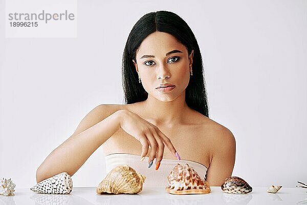 Schönheit Porträt der hübschen afro Frau mit verschiedenen Muscheln auf weißem Hintergrund. Weibliches Konzept