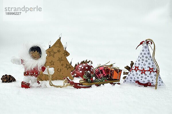 Weihnachstdekoration  Inuit zieht Schlitten mit Weihnachtsgeschenken durch den Schnee