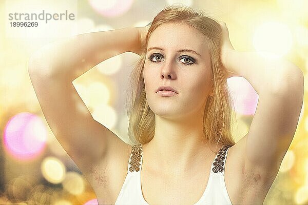 Close up Porträt der hübschen jungen blonden Frau hält ihr Haar  während Sie die Kamera auf abstrakte leuchtenden Hintergrund