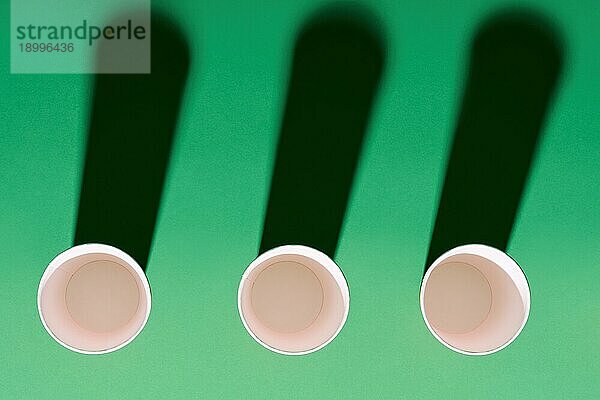 Draufsicht auf roten Pappbecher in Reihe auf grünem Hintergrund mit Schatten. kreatives Konzept  minimalistisch  moderne Kunst