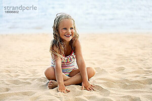 Adorable kleines Mädchen entspannen am Sandstrand im Sommerurlaub. Glückliche Kindheit Konzept