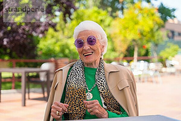 Eine ältere Frau tanzt im Garten eines Pflegeheims oder Seniorenheims auf einem Sommerfest und trägt dabei eine Sonnenbrille