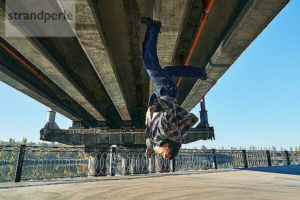 Junger Mann Breakdancer macht Salto akrobatische Stunts tanzen auf städtischen Hintergrund. Straßenkünstler Breakdance im Freien