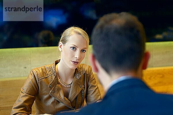 Blonde Frau im Gespräch mit einem Mann  ihrem Geschäftspartner  während sie einander gegenübersitzen