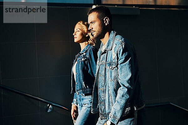 Modisches und selbstbewusstes junges Paar in Denim Jeans gehen nach oben in Richtung Sonne. Liebe  Beziehung und Erfolg Konzept