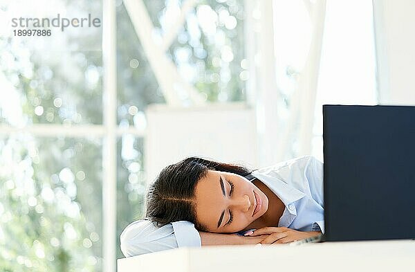 Müde überarbeitete Geschäftsfrau schläft am Arbeitsplatz auf dem Schreibtisch