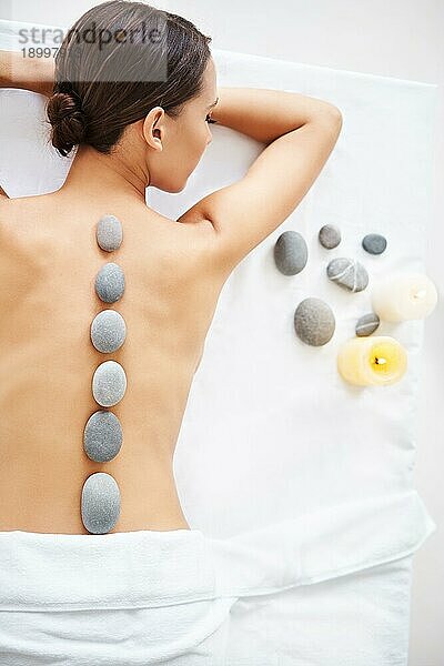 Schöne junge Frau entspannt sich bei einer Hot Stone Massage. Therapie  Schönheitsbehandlung Konzept