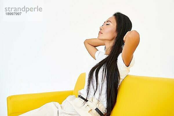 Junge hübsche Frau schloß die Augen sitzen auf gelben Sofa und entspannen nach anstrengenden Tag. Ruhe  Komfort Konzept