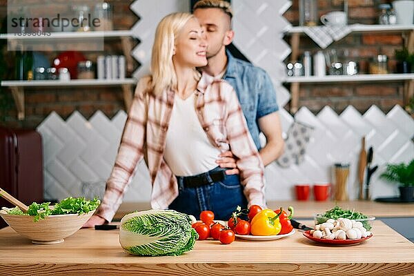 Vegetarisches Essen Konzept. Veganes Essen Kochen Zutaten auf dem Tisch und glücklich umarmt Paar auf dem Hintergrund