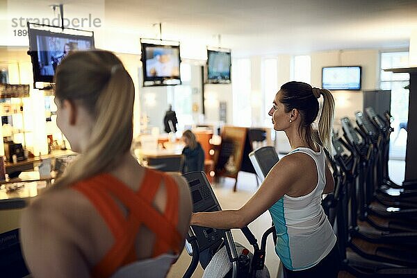 Seitenansicht einer Frau mittleren Alters an einem anaeroben Trainingsgerät im Fitnessstudio