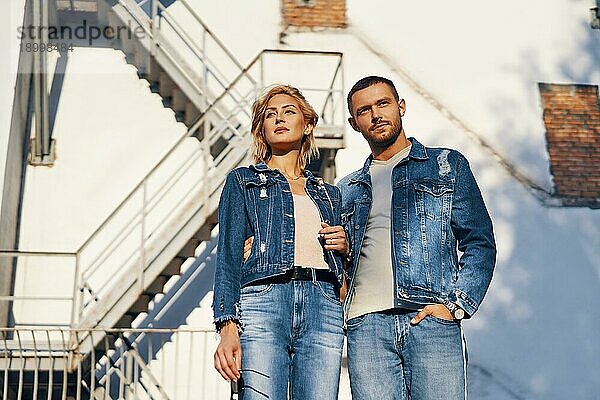 Junge schöne Frau und Mann in Jeans Stoff posiert auf städtischen Architektur. Paar Beziehung  Modekonzept