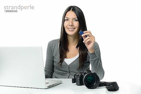 Attraktive Fotografin zeigt ihre SD Karte mit ihren neuen Bildern  die sie zur Bearbeitung auf ihren Laptopcomputer kopiert  vor weißem Hintergrund