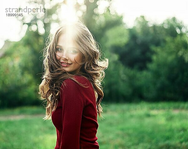 Junge schöne Frau mit Gegenlicht posiert im Freien auf grünen Sommer Natur Hintergrund. Weibliche Schönheit Konzept
