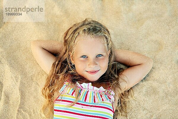 Hübsches kleines blondes Mädchen Porträt auf Sandstrand während der Sommerferien liegen. Meer entspannen  glückliche Kindheit Konzept