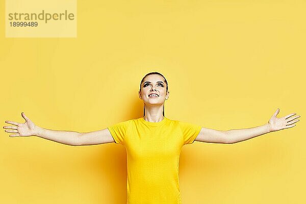 Glückliche Freiheit junge Frau mit erhobenen Händen Blick nach oben auf Kopie Raum über gelben Hintergrund Ausdruck Konzept