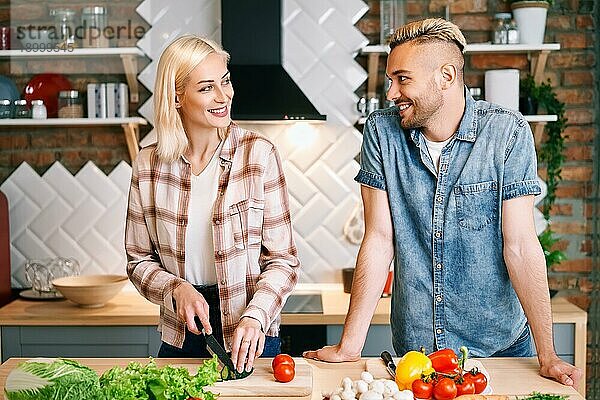 Lächelnd junges Paar Kochen zusammen vegetarische Mahlzeit in der Küche zu Hause. Gesunder Lebensstil Konzept