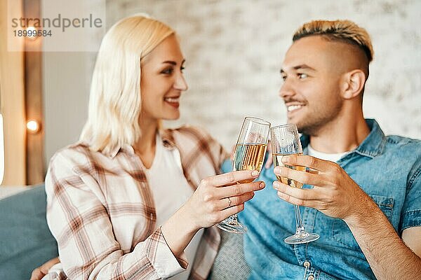Junges Paar stößt mit Weingläsern zu Hause an. Beziehung  Feier  Dating Konzept