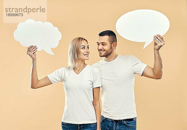 Lächelnde Frau und Mann halten Papier Gedankenblasen über beige Hintergrund. Beziehung Konzept