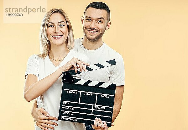 Junges glückliches Paar mit Kinoklappe. Mann umarmt eine Frau mit Filmklappe. Kinematographie Konzept