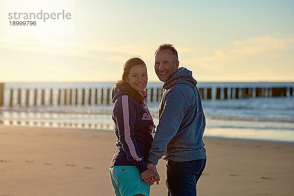 Glückliches  frisch entjungfertes Paar am Strand im Sommer lächelt in die Kamera