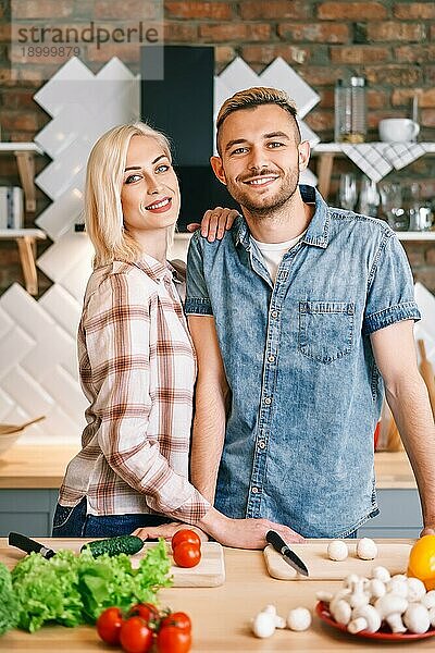 Lächelnde glückliches Paar kochen zusammen vegetarische Mahlzeit in der Küche zu Hause. Gesunder Lebensstil Konzept