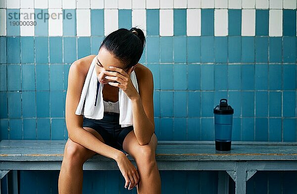Müde fit Frau mit einem Handtuch in der Umkleidekabine nach hartem Training. Stress  Sport  Versagen Konzept