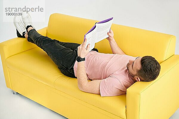 Mann entspannt sich auf dem Sofa und liest ein Buch. Ruhe  Hobby Konzept