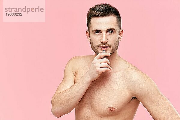 Porträt eines gut aussehenden jungen muskulösen Mannes mit nacktem Oberkörper  der in die Kamera schaut  auf rosa Hintergrund. Leerzeichen kopieren