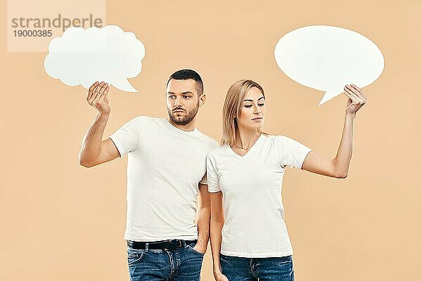 Upset Frau und Mann halten Papier Gedankenblasen über beige Hintergrund. Beziehung Konzept