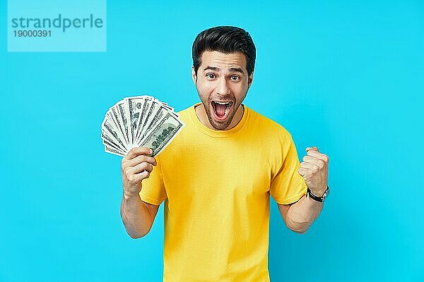 Glücklich aufgeregt Mann zeigt Geld Banknoten auf blauem Hintergrund. Geschäft  Gewinn  Einkommen  Erfolg Konzept