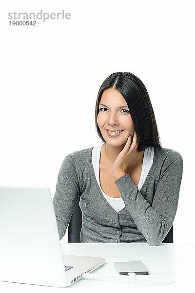 Frau sitzt konzentriert und schaut auf ihren Laptop mit angeschlossener externer Festplatte und ruhigem Lächeln  vor weißem Hintergrund