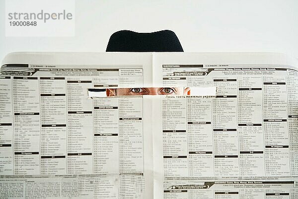 Privatdetektiv versteckt Uhren durch die Zeitung über weißen Hintergrund. Untersuchung  Geheimnis  Detektiv  Spionage Konzept