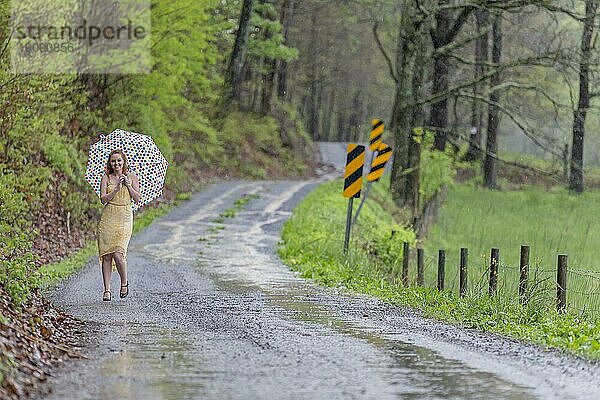 Ein rothaariges Modell posiert im Regen in einer Außenumgebung