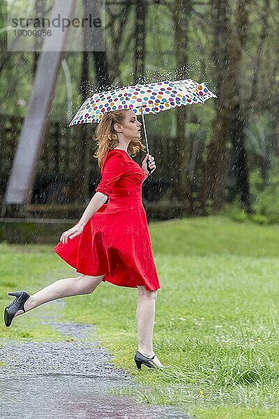 Ein rothaariges Modell posiert im Regen in einer Außenumgebung