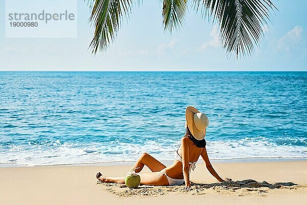 Junge schöne Frau sonnenbaden und entspannen sitzen allein auf tropischen Strand. Sommerurlaub Konzept