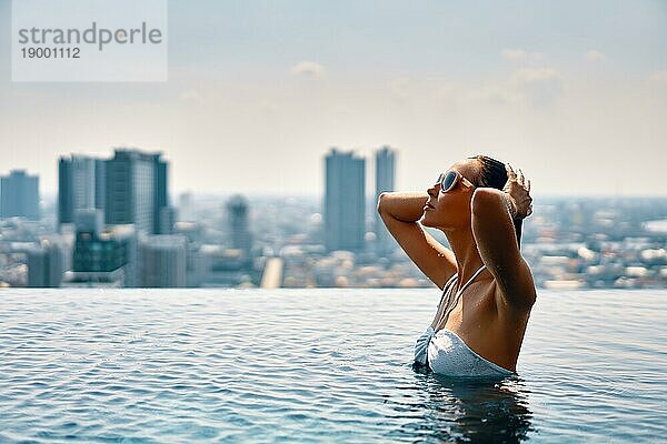 Junge schöne Frau genießen Sommerurlaub am Swimmingpool im Hotel Dach oben. Reisen und entspannen Konzept