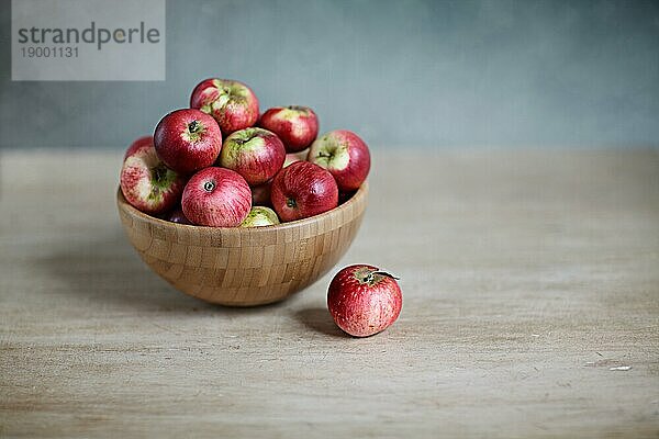 Stillleben mit kleinen roten Äpfeln in Holzschüssel
